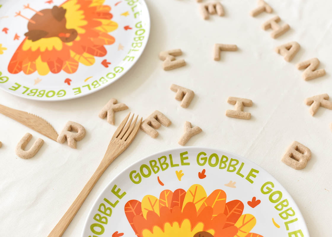 Cropped Close up of Two Place Settings using Thanksgiving Turkey Melamine Dinner Platess with Alphabet Letters on Table