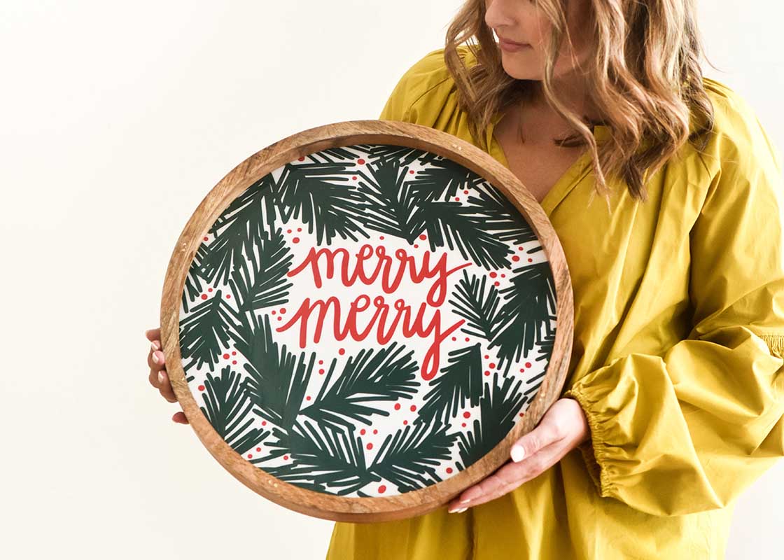 Front View of Woman Holding and Admiring Holly Wood Handled Round Tray in Front of Her