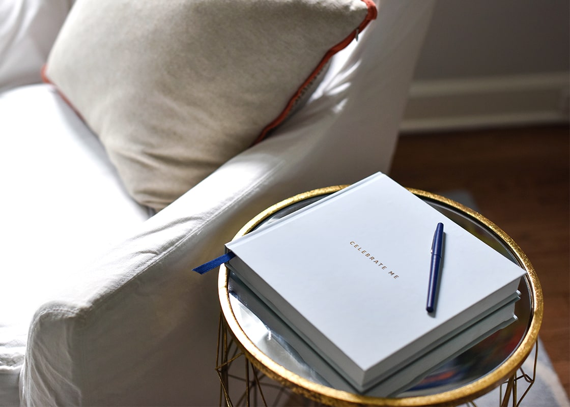 Front View of Keeping the Celebrate Me Book Close on a Small Table next to Couch to Jot Down the Day's Thoughts