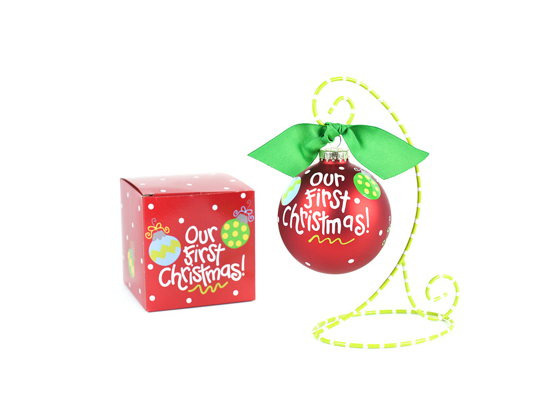 Front View of Our First Christmas Glass Ornament Placed on Green and White Stripe Display Stand with Matching Box