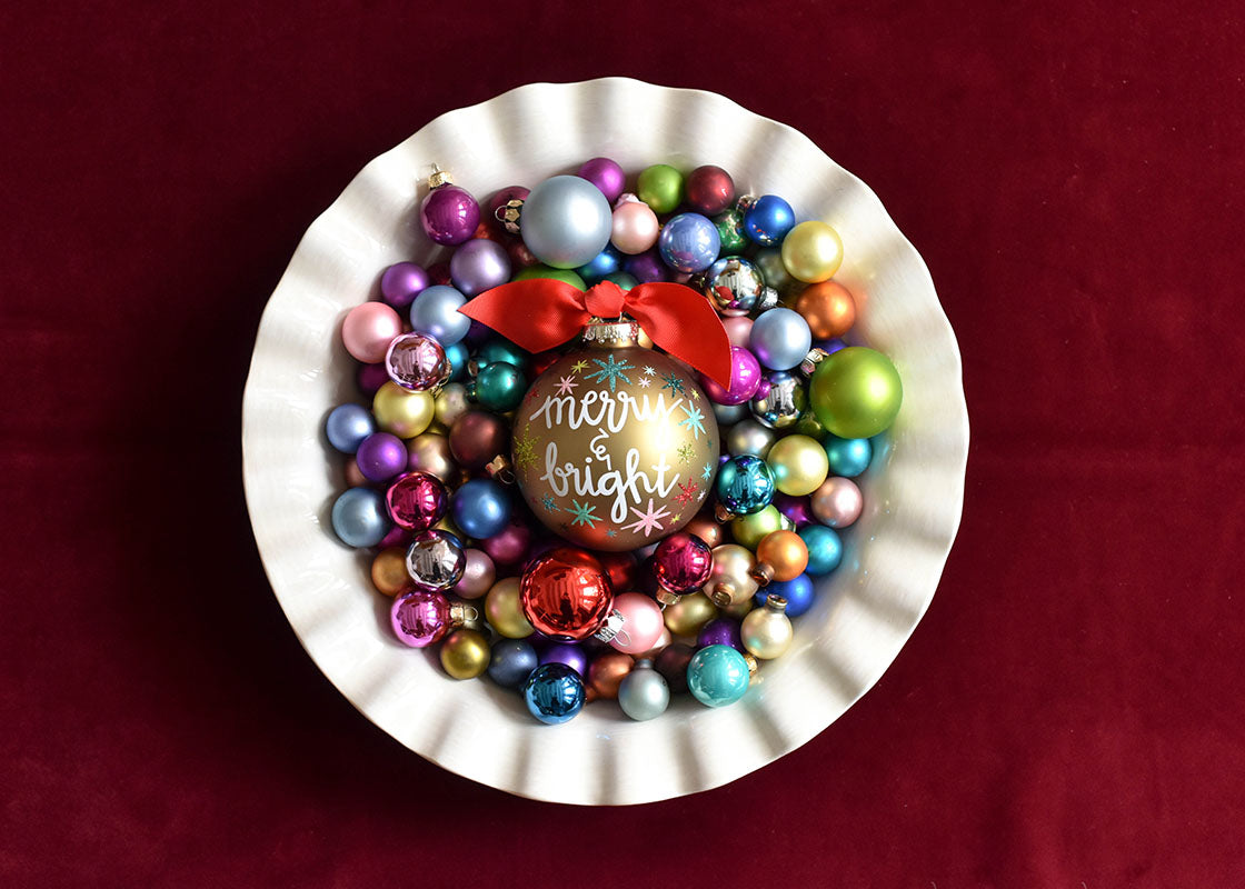 Overhead View of Bowl Filled with small Colorful Ornaments Including Merry and Bright Stars Glass Ornament in Center