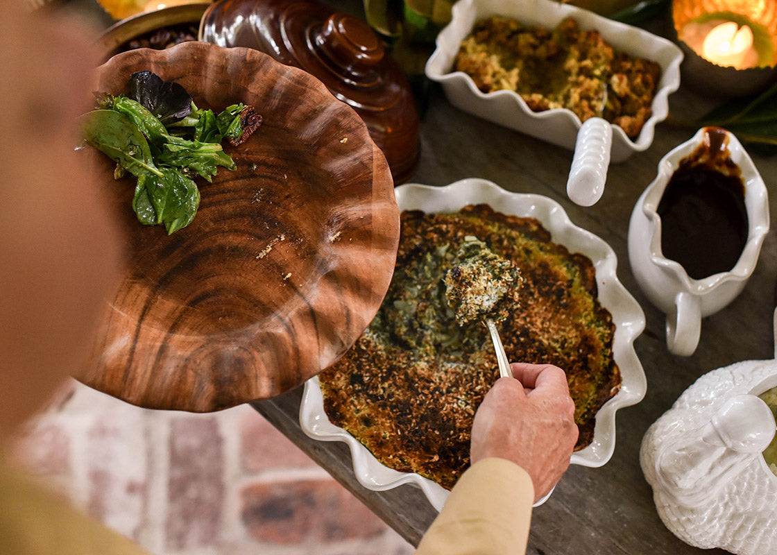 Overhead View of Person Dishing up Spinach onto Fundamental Wood Ruffle Dinner Plate