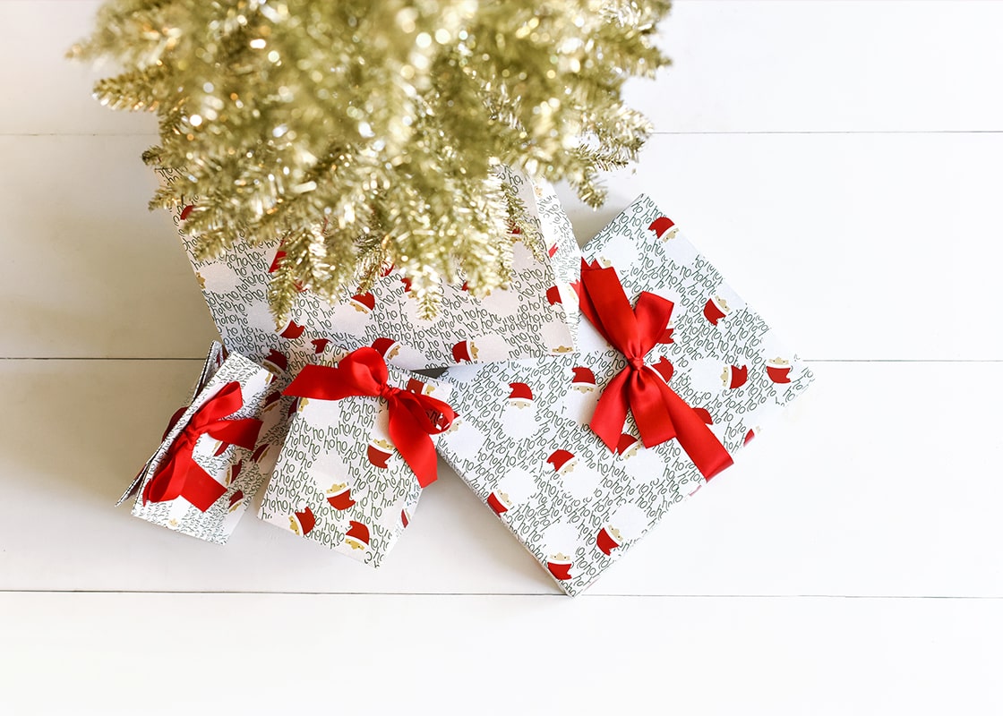 Overhead View of Ho Ho Santa Design Wrapping and Bags Under Gold Tinsel Tree