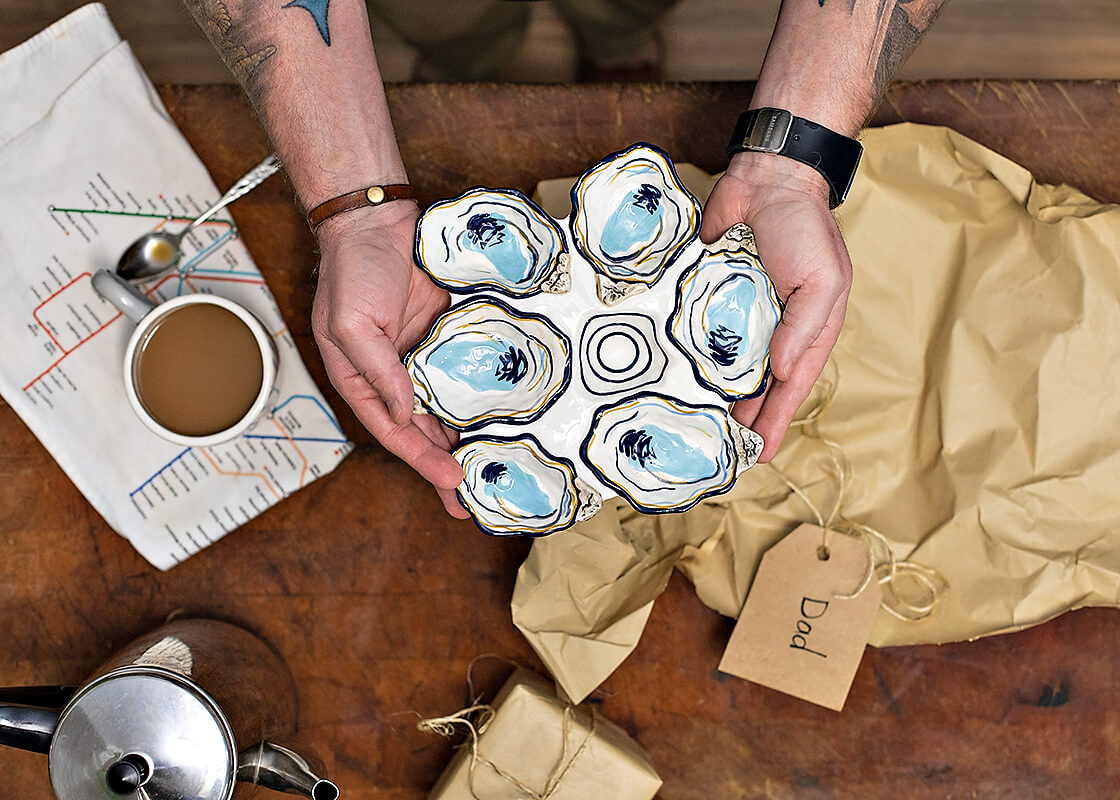 Overhead View of Dad Holding a Recently Unwrapped Gift of Oyster Half Dozen Platter