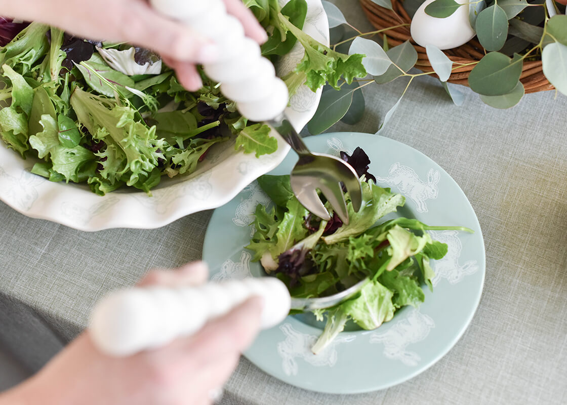 Close up of Hands Using Servers to Place Salad onto Speckled Rabbit Rimmed Salad Plate