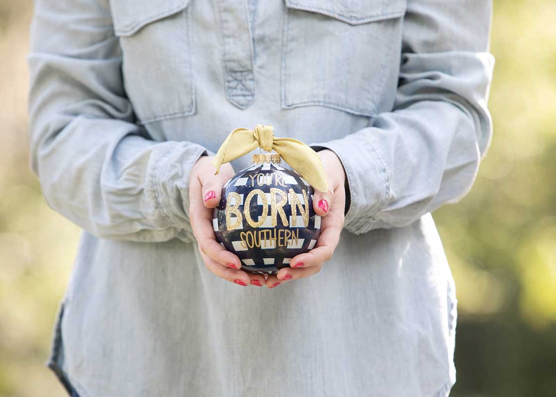Front View of Person Holding Gift You're Born Southern Glass Ornament with Both Hands