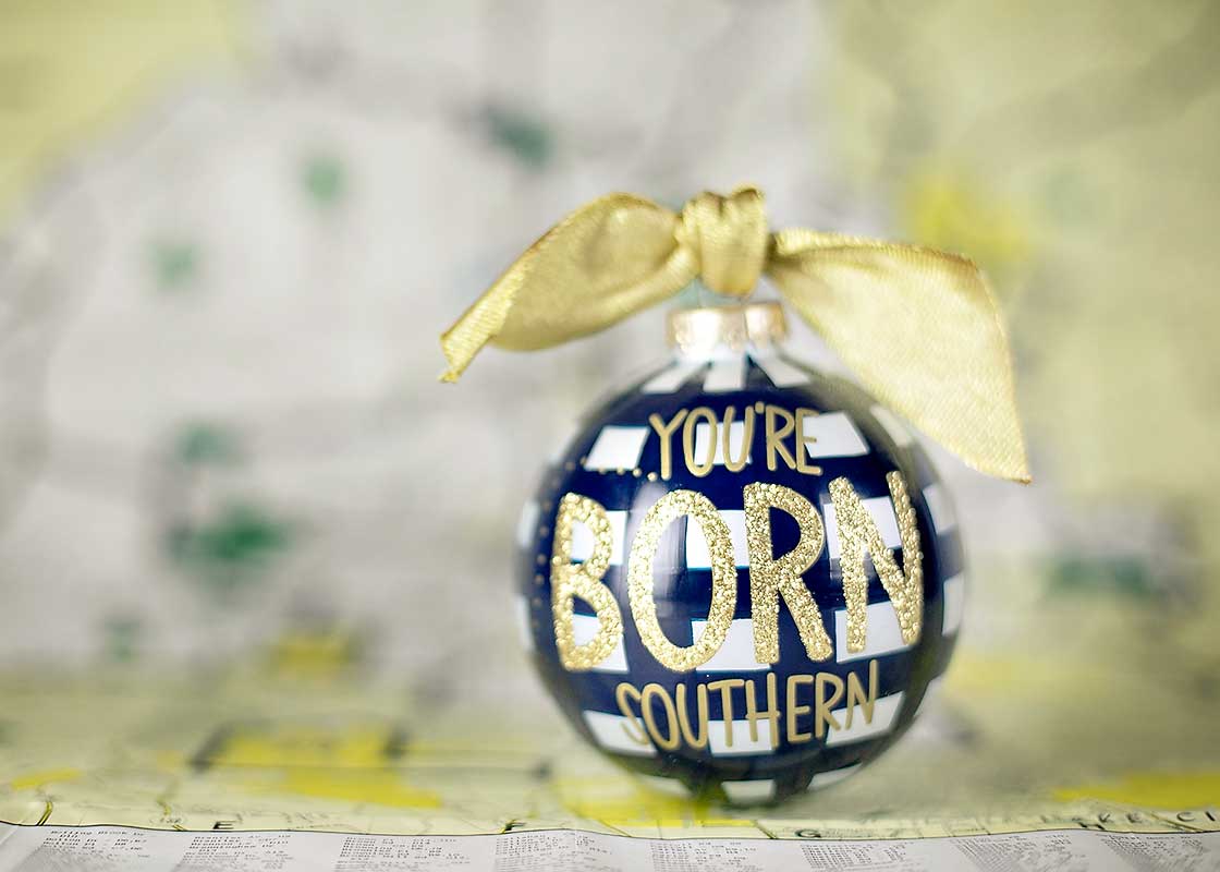Front View of Blue Check Glass Ornament Born Southern Design Placed in Front of Map of the South