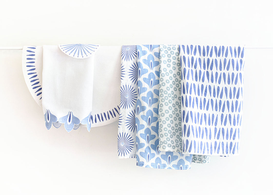 Front View of Linen Hand Towels in Iris Blue Designs Including Iris Blue Sprout Hand towel Folded and Hanging on Rod
