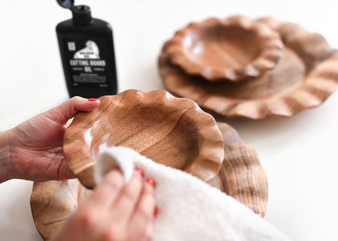 Front View of Hands Rubbing Wood Treatment Oil onto Plate Surface Showing Easy Care of Fundamentals Collection
