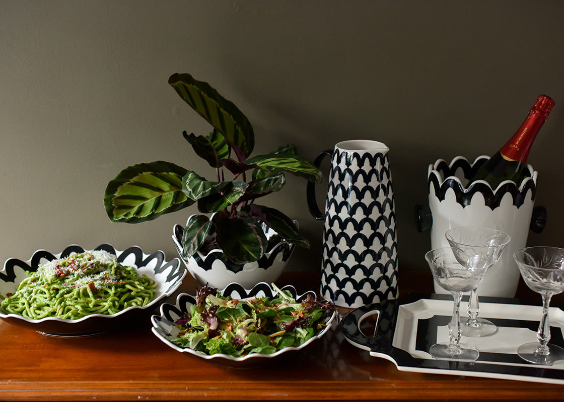 Front View of Black Arabesque Pedestal Pitcher set on Buffet Table Filled with Coordinating Pieces from Crew Collection