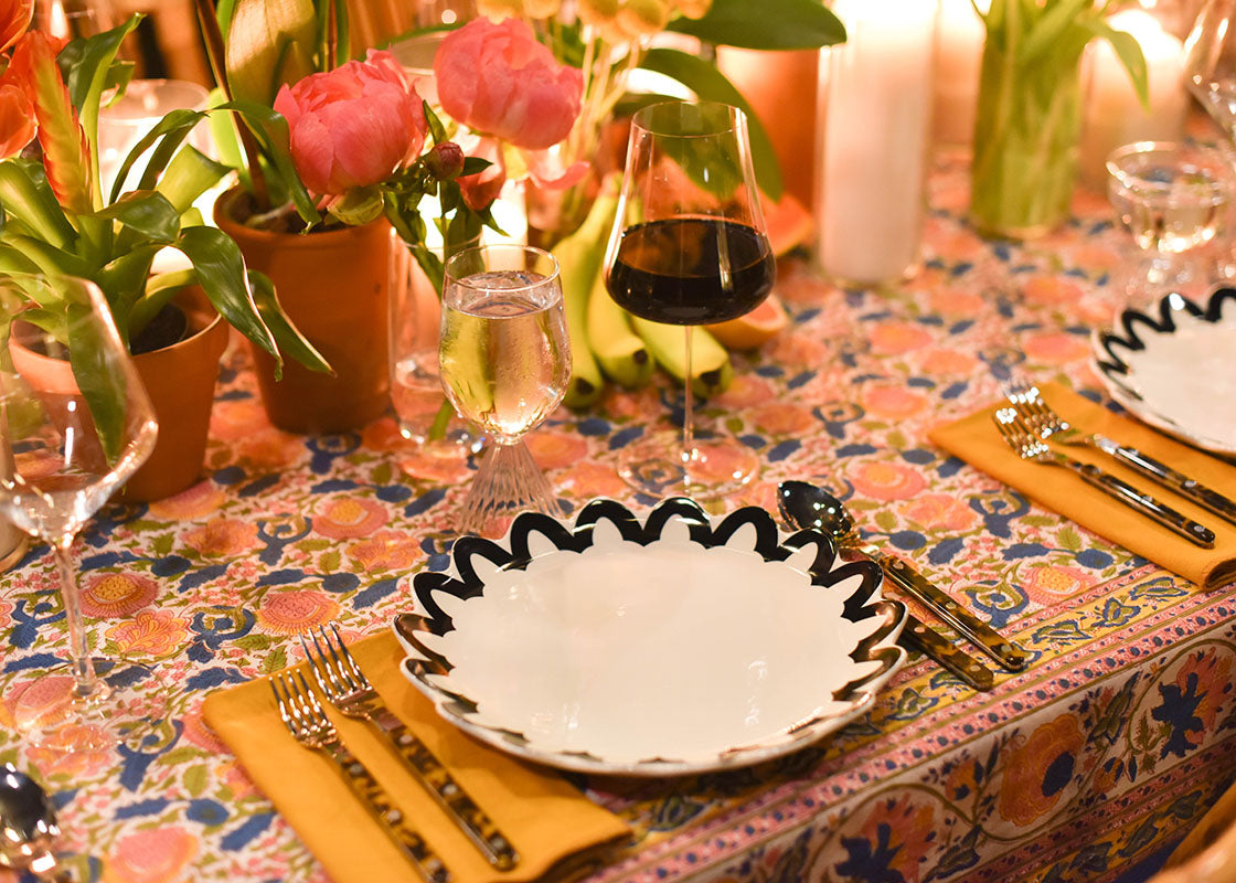 Close up of Black Arabesque Trim Scallop Dinner Plate set on Colorful Tablecloth in Beautiful Tablescape