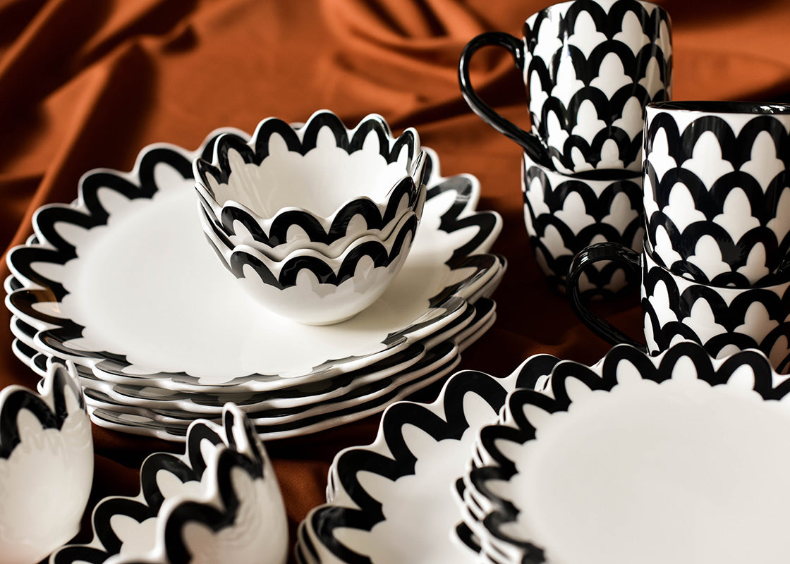 Front View of Stacks of Black Arabesque Scallop 4 Piece Place Settings from Crew Collection Including Plates, Mugs and Bowls