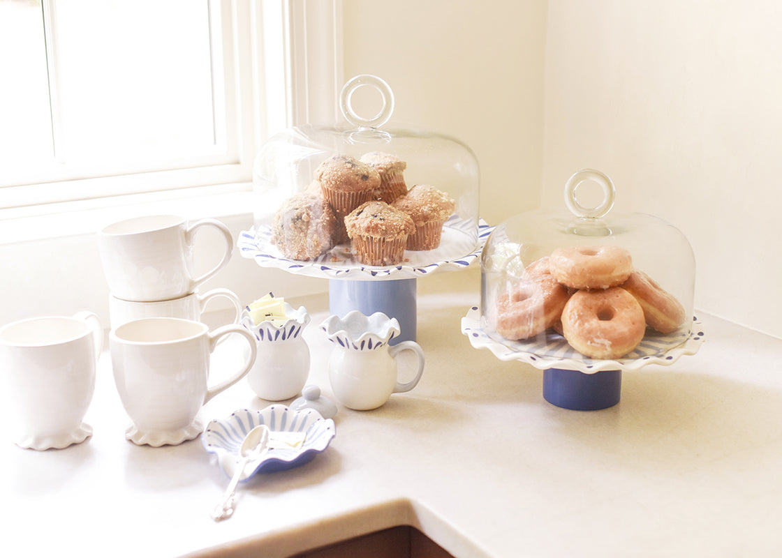 Front View of Two Iris Blue Cake Stands with Glass Domes Covering Stacks of Muffins and Donuts with Coordinating Serveware