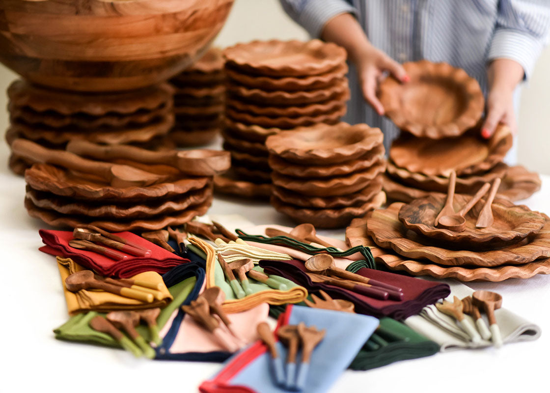 Cropped Close up of Woman Placing Dishes next to Fundamental Wood 11in Ruffle Bowl on Table