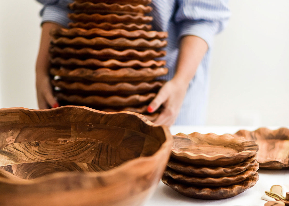 Cropped Close up of Woman Placing Stack of Wooden Plates next to Fundamental Wood 11in Ruffle Bowl