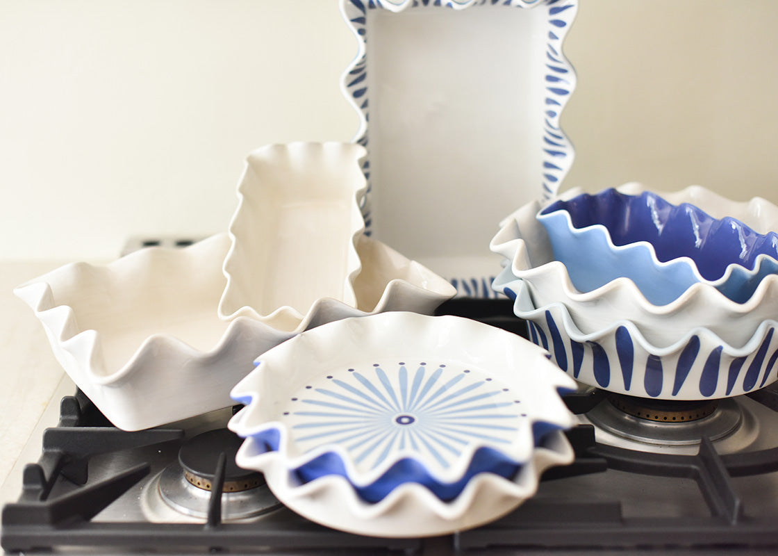 Front View of Stacks of Bakeware Including Iris Blue Ruffle Loaf Pan Placed on Cooktop