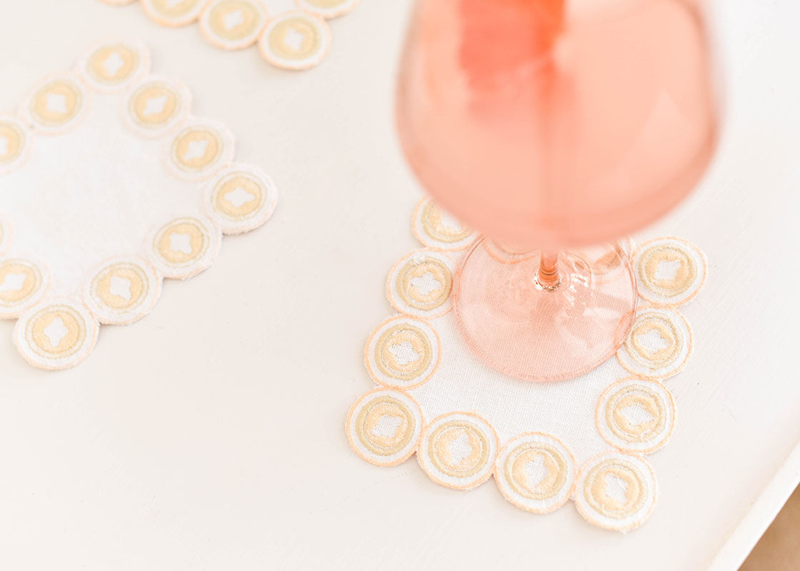 Cropped Close up of Pretty Glasses Placed on Cocktail Napkins with Blush Arabesque Design