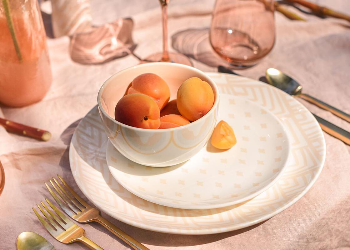 Front View of Blush Arabesque Small Trim Bowl with Coordinating Tableware Designs Filled with Nectarines