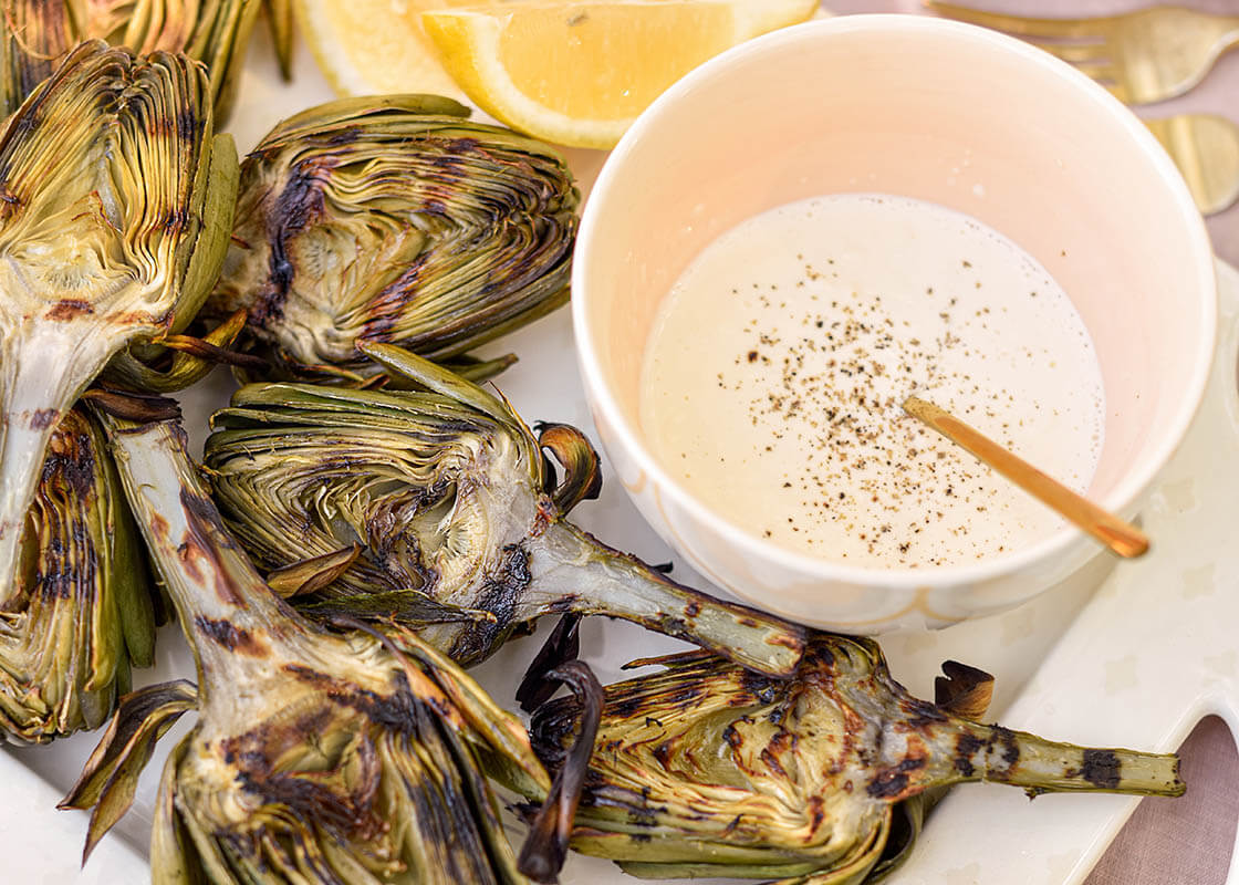 Overhead View of Roasted Artichokes with Dipping Sauce Served in Blush Arabesque Trim Small Bowl