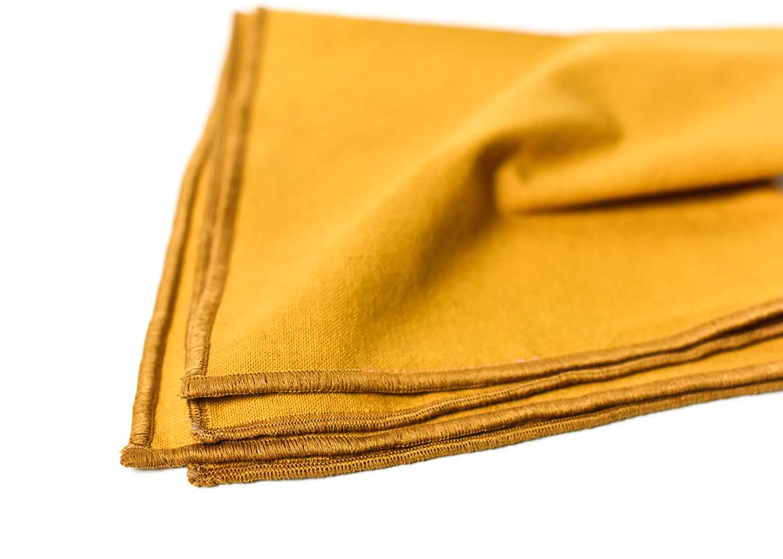 Cropped Close up of Colorful Hem Stitching on Folded Brass Color Block Napkins Set of 4 Showcasing Beautiful Texture of Fabric