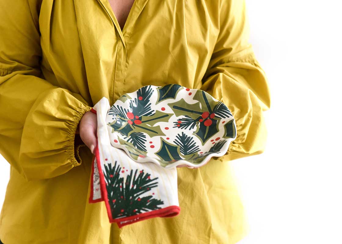 Cropped Close up of Woman in Lime Green Dress Holding a Holly Ruffle Salad Plate and Coordinating Napkin in Front of Her