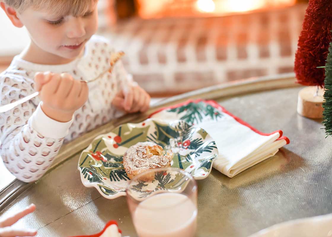 Front View of Child Sitting at Table Enjoying a Cinnamon Roll from Holly Ruffle Salad Plate on Christmas Morning