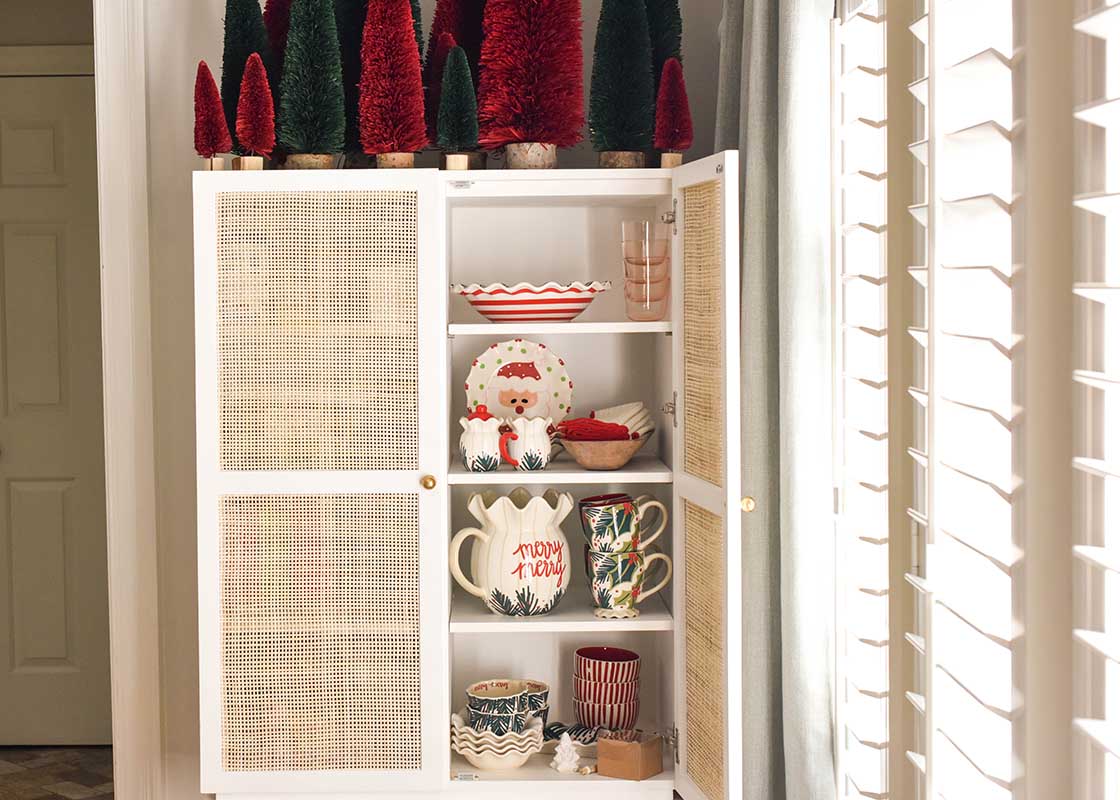 Cropped View of Cupboard Full of Christmas Dishes including Stacks of Holly Ruffle Mugs