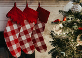 Three Red Buffalo Check Pattern Stockings Hung by a Fireplace Near the Christmas Tree