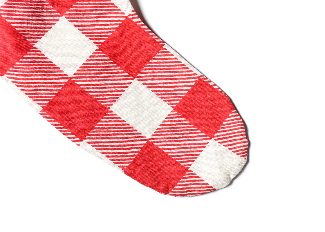 Front View of Three Red Buffalo Check Pattern Stockings Hung by a Fireplace Near the Christmas Tree