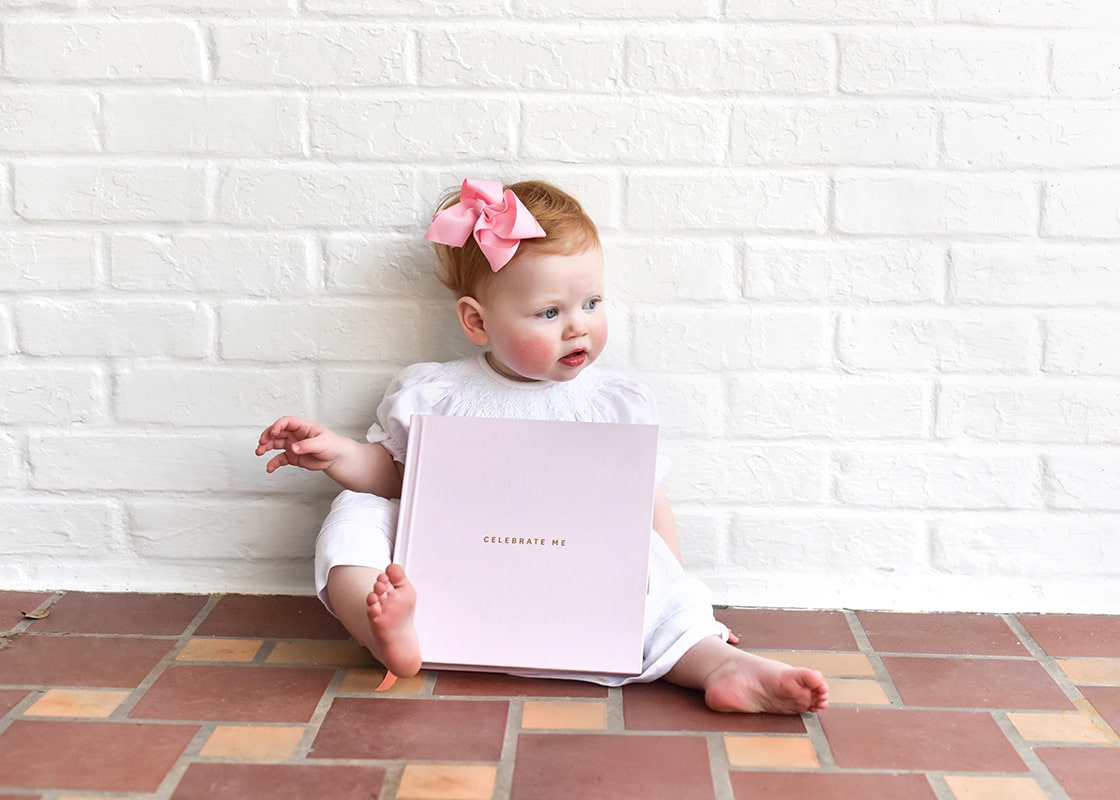 Front View of Seated Baby Girl with Pink Celebrate Me Book