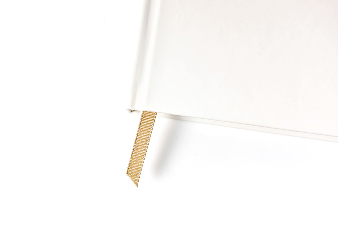 Cropped Close up of White cover and Hold your Place Gold Ribbon in Celebrate Us Book