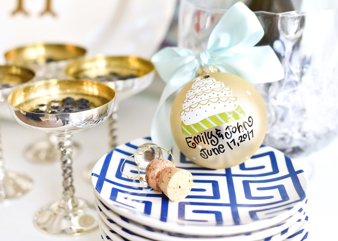 Front View of Personalized Wedding Cake Ornament Placed On a Stack of Plates Amidst a Celebratory Tablescape Personalized with Emily and John June 17, 2017