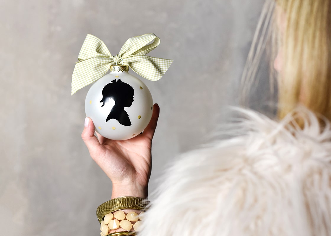 Back View of Woman Holding in Palm of Hand Girl Silhouette Ornament with Oversized Check Bow