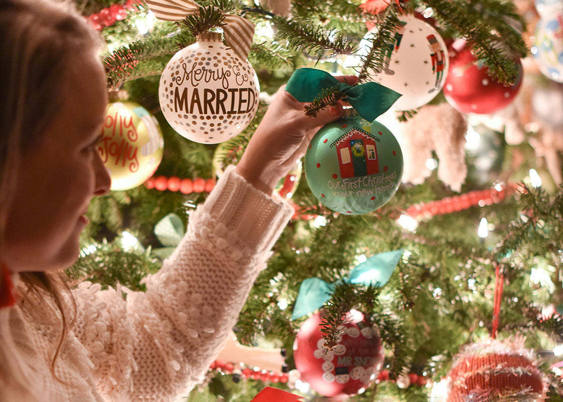 Front View of Woman Hanging Our First Christmas in Our New Home Ornament on Lighted Tree