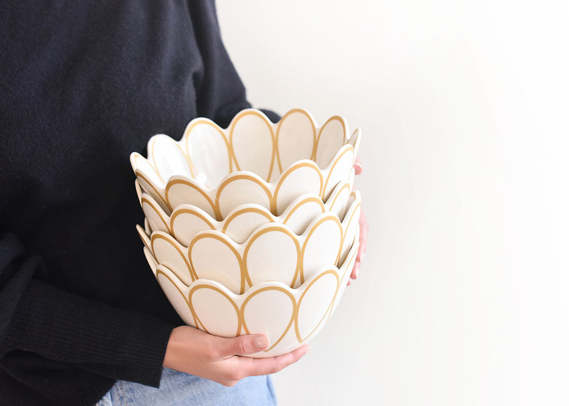 Close up of Woman Holding a Stack Deco Gold Scallop Serving Bowls