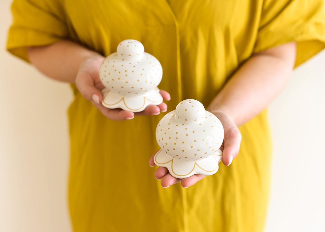 Front View of Woman Holding Deco Gold Scallop Salt and Pepper Shaker Set in Front of Her