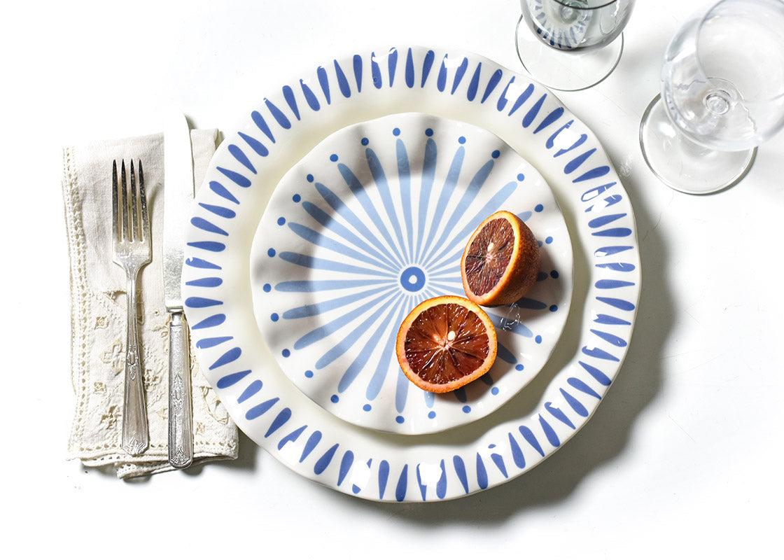 Overhead View of a Coordinated Place Setting including an Iris Blue Drop Ruffle Dinner Plate with a sliced Blood Orange placed on top