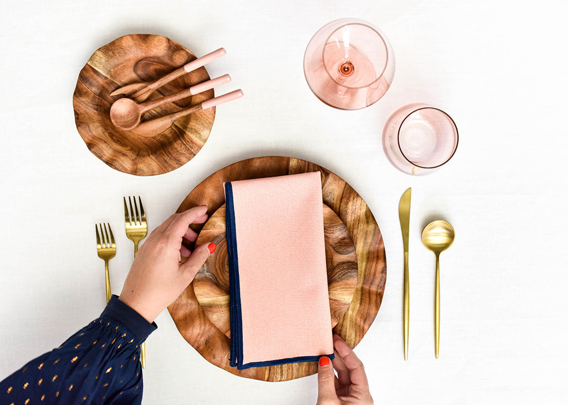 Overhead View of Hands Adjusting Napkin of Blush Tablescape with Wood Ruffle Dinner Plate
