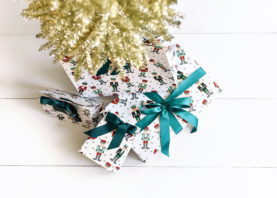 Overhead View of Nutcracker Large Christmas Bag for Gifts Under Gold Tinsel Tree with many Wrapped Packages