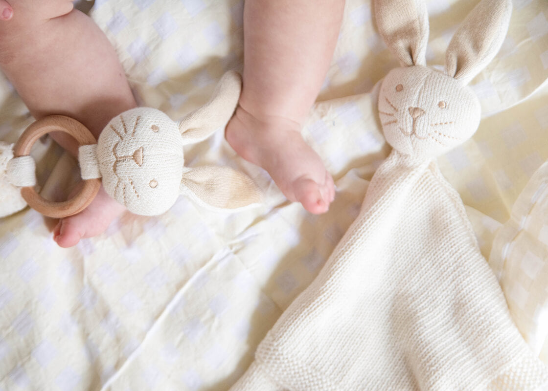 Extreme Cropped Close up of Baby Sitting on  Ecru Gingham Swaddle with Toys