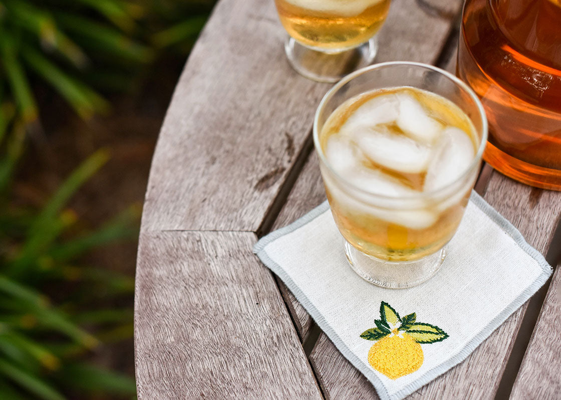 Overhead View of Cocktail Placed on Soft Linen Cocktail Napkin with Lemon Citrus Embroidered Design