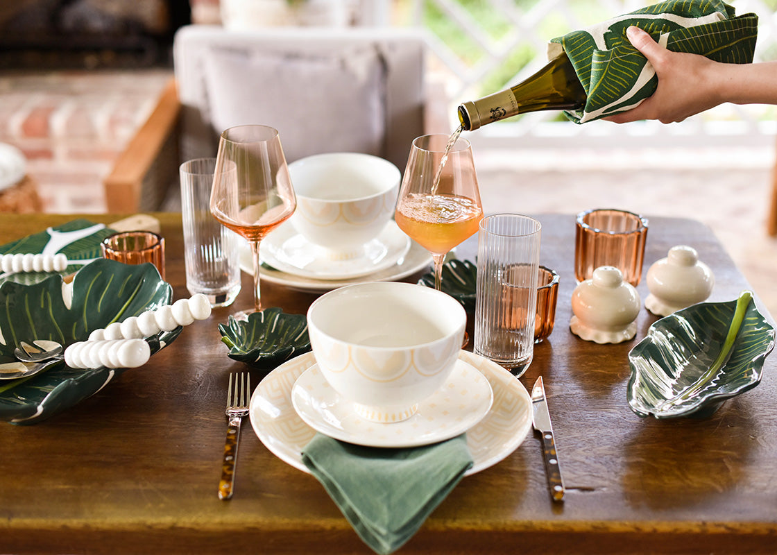 Cropped View of a Pretty Tablescape with Hand Pouring Wine from a Bottle Wrapped in Palm Hand Towel