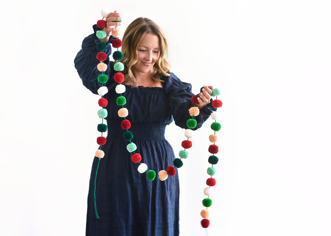 Cropped View of Woman Holding Up Mint Multi Pom Pom Garland and Smiling