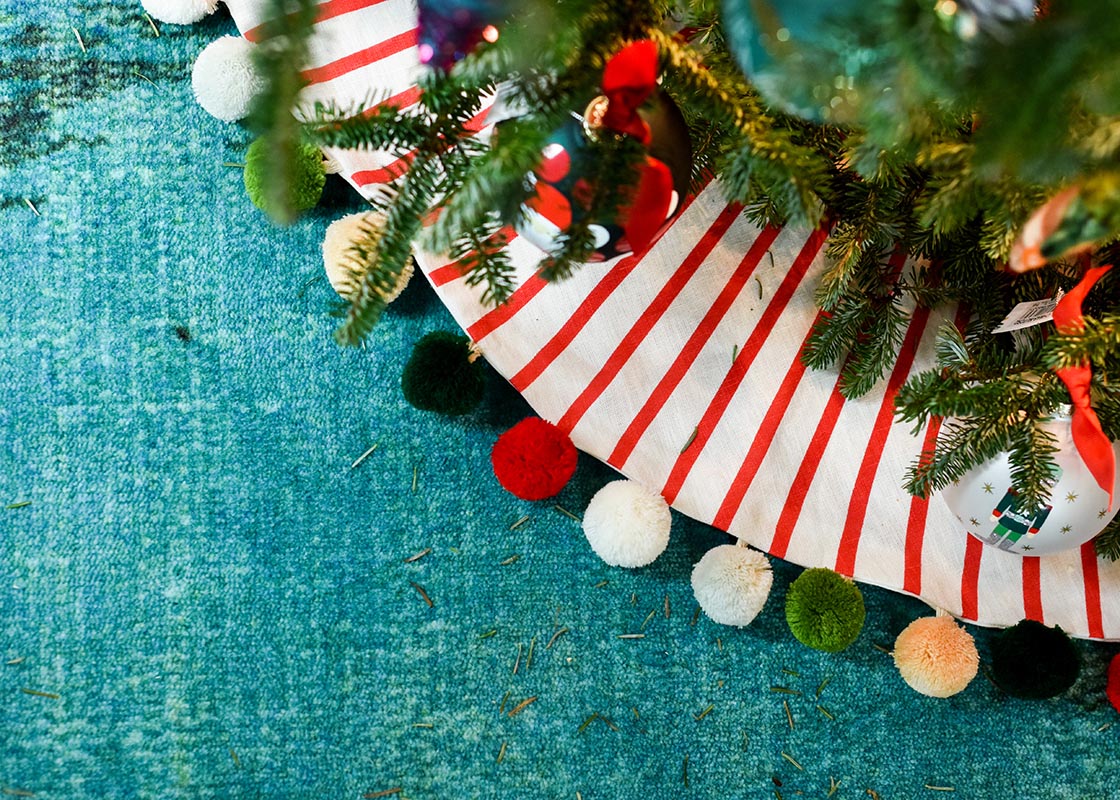 Overhead View of Tree Skirt with Pom Poms and Red Stripes Under Christmas Tree