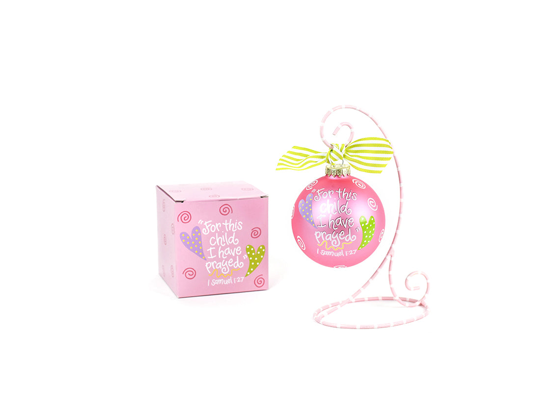 Front View of Pink For This Child Glass Ornament Placed on Pink and White Stripe Display Stand and Matching Box