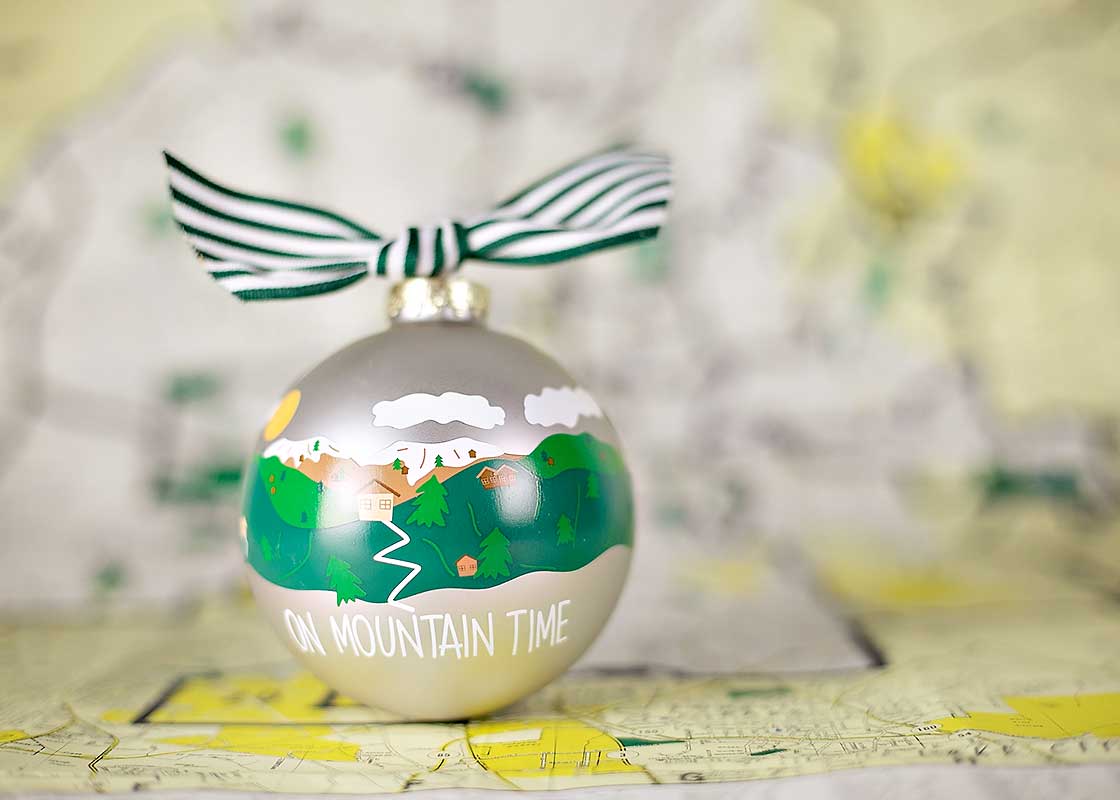 Front View of Hand-painted Mountain Landscape On Mountain Time Ornament Placed in Front of Map