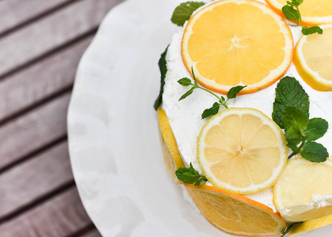 Cropped Close up of Ruffle Edge Signature White 14 inch Cake Stand Serving Beautiful White Cake Decorated with Citrus Slices and  Fresh Mint Leaves