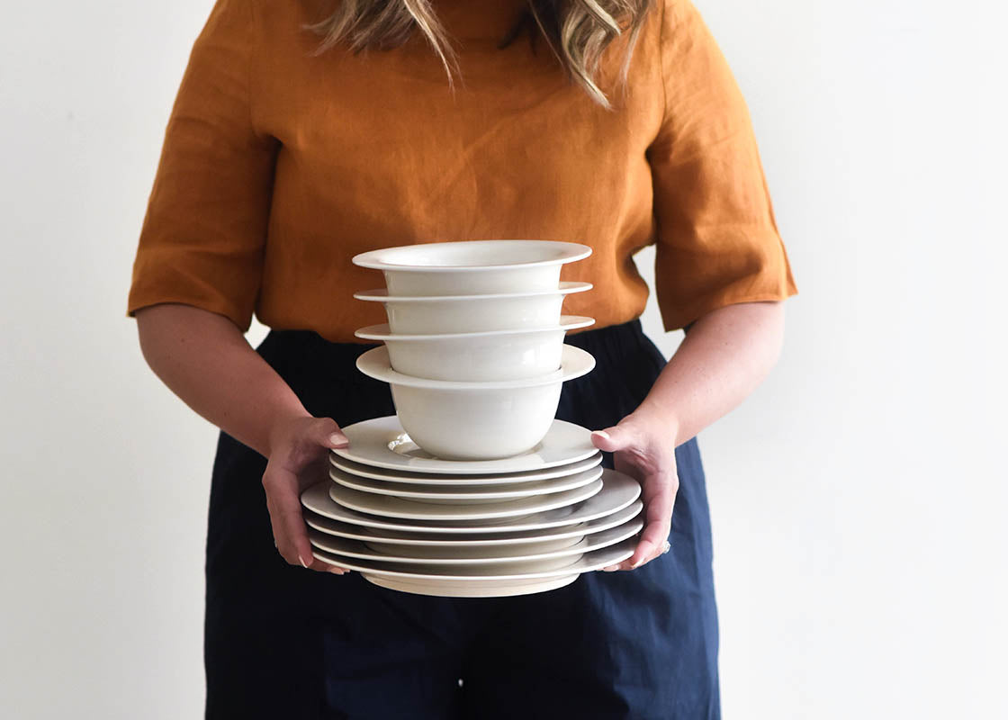 Front View of Woman Holding Stacked Signature White Rimmed 4 Piece Place Settings with Signature White Rimmed Small Bowl on Top