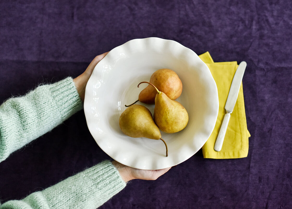 Overhead View of Hands Holding Ruffle Best Bowl Signature White Serving Fruit