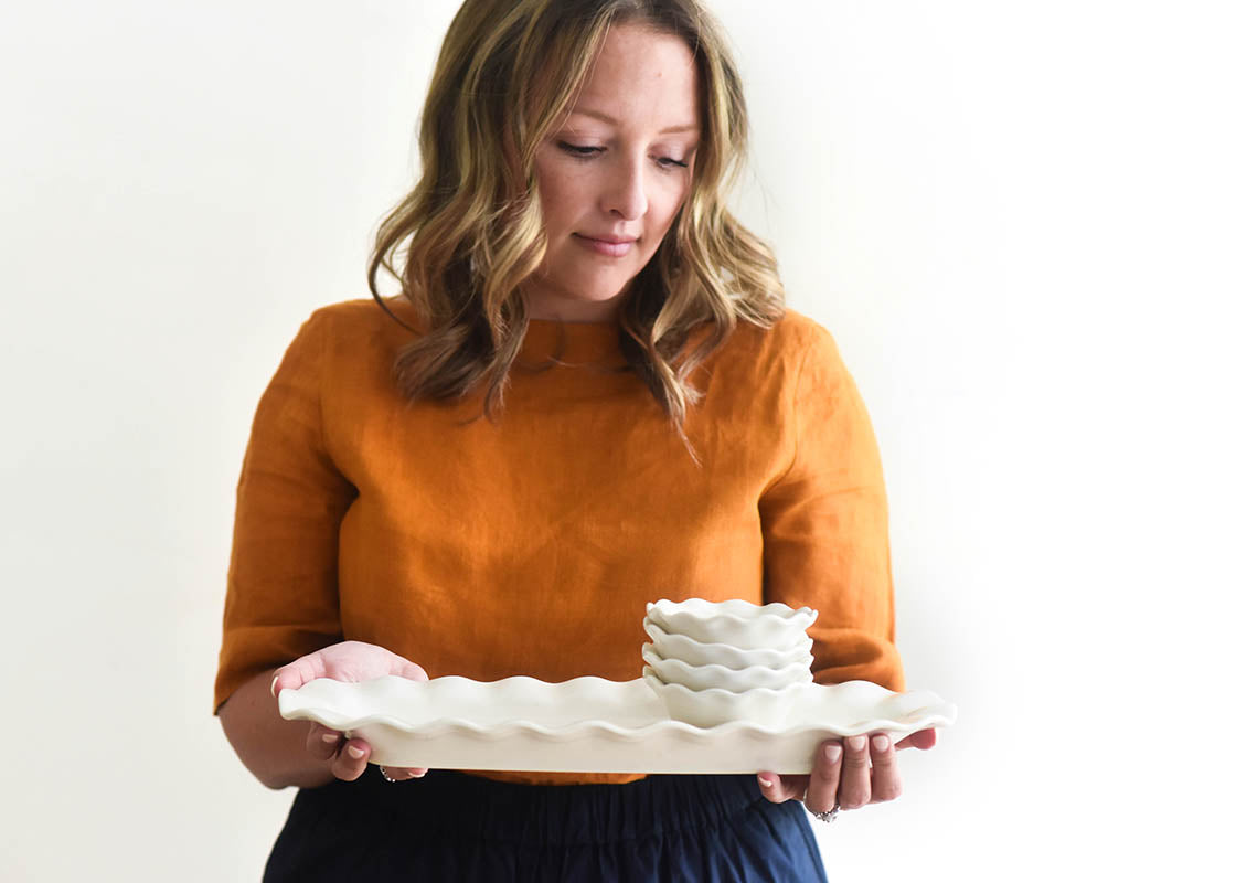 Cropped View of Woman Holding Signature White Ruffle Skinny Tray with Stack of Bowls on Top